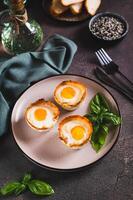 Baked egg and bacon rolls with basil on a plate on a table vertical view photo