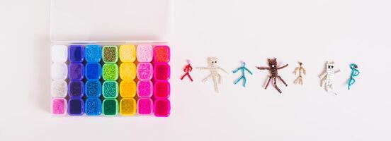 Box with multi-colored beads and woven figures on the table top view web banner photo