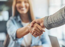 A happy businesswoman shakes hands with a new employee in the office. A smiling young woman and a man shaking hands when signing a contract photo