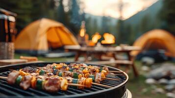 Camping scene with skewers grilling on a BBQ, tents in the background, and a warm campfire at sunset in a forest setting. photo
