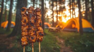 Grilled skewers cooking over a campfire with tents set up in the background, capturing the essence of outdoor camping at sunset. photo
