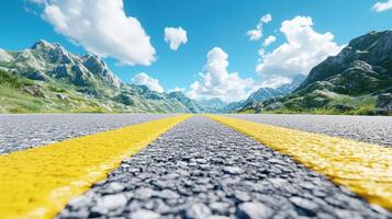 Picturesque highway extending into a scenic mountain landscape under a vibrant blue sky with fluffy clouds. photo