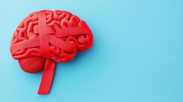 Red brain model wrapped with red tape on a blue background, symbolizing mental health issues, brain injury, or cognitive challenges. photo