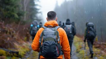 Group of hikers in rain jackets with backpacks trekking through a misty forest on a rainy day in autumn. photo