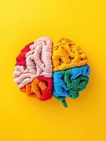 Colorful yarn brain on a vibrant yellow background, representing creativity, intelligence, and mental health in a fun, artistic way. photo