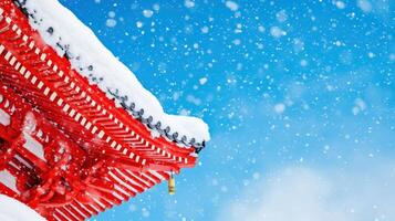 A beautiful snow-covered rooftop with vibrant red architecture against a clear blue sky, creating a picturesque winter scene. photo