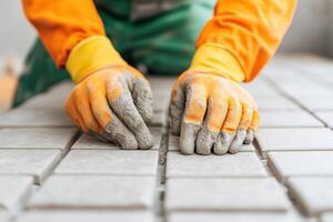 A worker lays tiles with gloved hands, showcasing precision and skill in masonry construction. photo