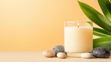 A serene setting featuring a lit candle, smooth stones, and lush leaves, creating a peaceful and relaxing atmosphere. photo
