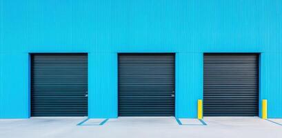 Vibrant blue wall with three black garage doors, showcasing modern architecture and clean lines in an urban setting. photo