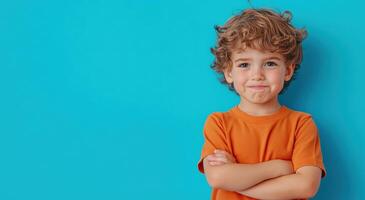 A cheerful boy with curly hair poses confidently in front of a bright blue background, showcasing a playful spirit. photo