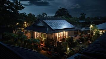A cozy house with solar panels on the roof is illuminated at night by warm lights, surrounded by lush greenery. photo
