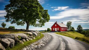 A red cottage sits at the end of a winding road, with a large tree and a stone wall, with a clear blue sky and fluffy white clouds. photo