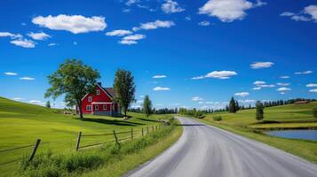 A winding road leads through a picturesque landscape with a red farmhouse, lush green fields, and a blue sky with fluffy white clouds. photo