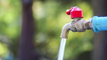 Close-Up of Outdoor Water Faucet with Flowing Water Against Blurred Green Background photo
