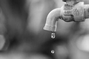 Close-Up of a Dripping Water Faucet in Black and White Highlighting Water Conservation and Environmental Awareness photo