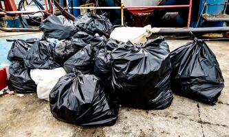 Pile of Black Garbage Bags on Concrete Ground in Urban Setting photo