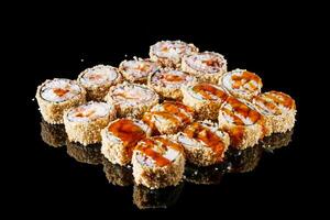 hot sushi roll tempura with eel shrimp crab salmon cream cheese cucumber avocado unagi on a black mirror background photo