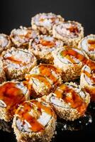 hot sushi roll tempura with eel shrimp crab salmon cream cheese cucumber avocado unagi on a black mirror background photo