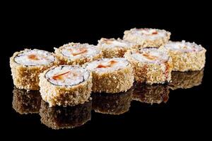 hot sushi roll tempura with eel shrimp crab salmon cream cheese cucumber avocado unagi on a black mirror background photo