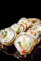 hot sushi roll tempura with salmon cream cheese cucumber avocado unagi on a black mirror background photo