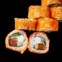 sushi roll with salmon cream cheese tobiko avocado and cucumber on a black mirror background photo