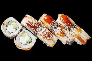 sushi roll with avocado cucumber cream cheese eel unagi on a black mirror background photo