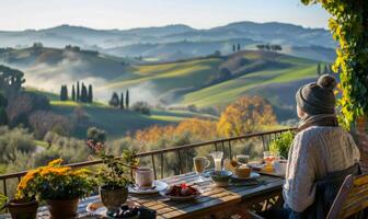A cheerful person enjoying breakfast on their balcony with a panoramic view of rolling hills photo