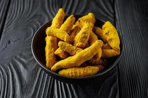 aromatic turmeric root on a black wooden rustic background photo