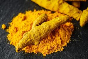 aromatic turmeric root on a black wooden rustic background photo