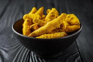 aromatic turmeric root on a black wooden rustic background photo