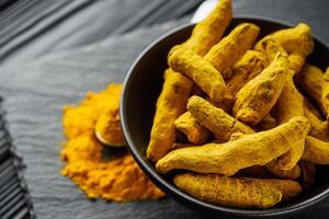 aromatic turmeric root on a black wooden rustic background photo