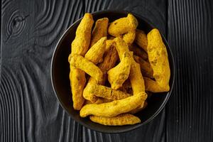 aromatic turmeric root on a black wooden rustic background photo
