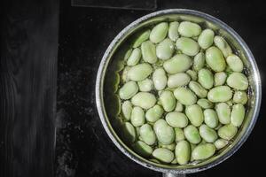 fresh greens broad beans fava boiled on a dark background photo