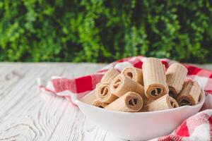 crispy dessert wafer rolls on a white wooden rustic background photo