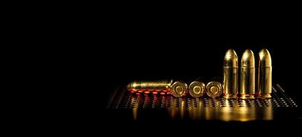 Pistol cartridges 9 mm on a smooth glossy surface with reflections. Ammunition for pistols and PCC carbines on a dark back. photo
