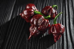 fresh brown extra hot carolina reaper chocolate pepper on black wooden rustic background photo