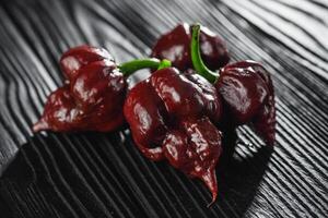 fresh brown extra hot carolina reaper chocolate pepper on black wooden rustic background photo