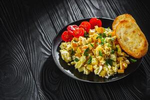 tasty scrambled eggs with zucchini on a black rustic rustic background photo