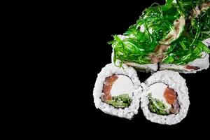 sushi roll with tuna cucumber cream cheese and chuka on a black mirror background photo
