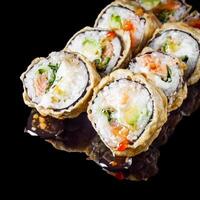 hot sushi roll tempura with salmon cream cheese cucumber avocado unagi on a black mirror background photo