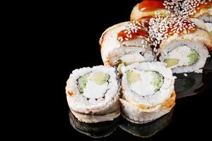sushi roll with avocado cucumber cream cheese eel unagi on a black mirror background photo