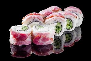 sushi roll with cream cheese cucumber bacon on a black mirror background photo