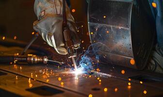 A close-up of a welder's hands and tools in action, sparks flying photo