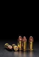 Pistol cartridges 9 mm on a smooth glossy surface with reflections. Ammunition for pistols and PCC carbines on a dark back. photo