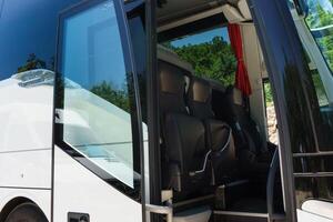 Modern buses for transporting people stand at the bus stop. Close-up of an open bus door. Light back. photo