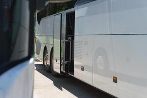 Modern buses for transporting people stand at the bus stop. Close-up of an open bus door. Light back. photo