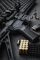 Modern automatic carbine with optical and collimator sight. A rifle with two sights on a dark background. Cartridges for weapons near a carbine. photo