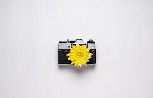 Vintage camera with a yellow flower instead of a lens. old camera on a white background. Instead of a lens, a flower with yellow petals photo