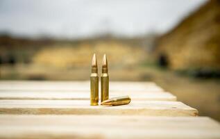 308 caliber ammunition for a rifle standing on a wooden table on the background of the shooting range photo