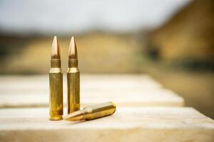 308 caliber ammunition for a rifle standing on a wooden table on the background of the shooting range photo